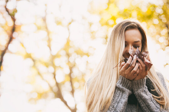 Autumn: Woman Smelling A Handful Of Fall Leaves