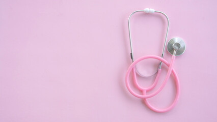 Fototapeta premium Minimal medical background with pink stethoscope placed on the right side of pink canvas