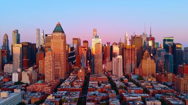 Sunset light on Midtown Manhattan towers from Chelsea, New York. North along a street canyon toward Billionaires Row supertalls bathed in warm orange and pink dusk glow.