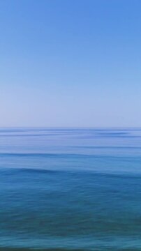 aerial view of a beach and ocean with surfers having fun on a bright summer day - vertical video for story and reel