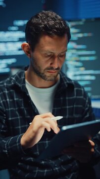 Vertical Screen : Young Caucasian male programmer use tablet for code design and plan in office at night. AI technology, cybersecurity, software developer, freelance innovation, digital data network.