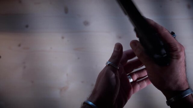 Close-up of hands holding a black semi-automatic pistol, depicting dangerous illegal activities and criminal weapon possession in a moody cinematic style.