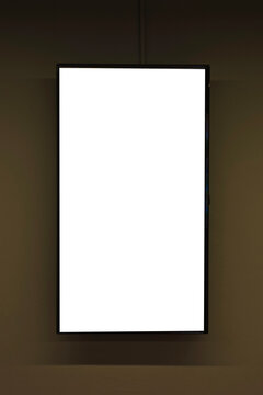 Blank vertical digital screen display with empty white copy space hanging on a brown wall background