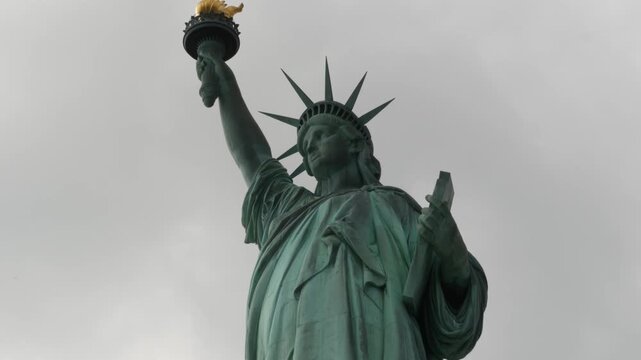 Statue of Liberty on Liberty Island, New York, United States. Blue cooper monument, symbol of democracy and patriotism near Manhattan, NYC USA. Clouds on sky. American independence. Torch and crown.