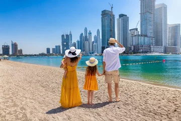 A beautiful tourist family walks at a city beach with view of the Dubai Marina skyline, UAE © moofushi