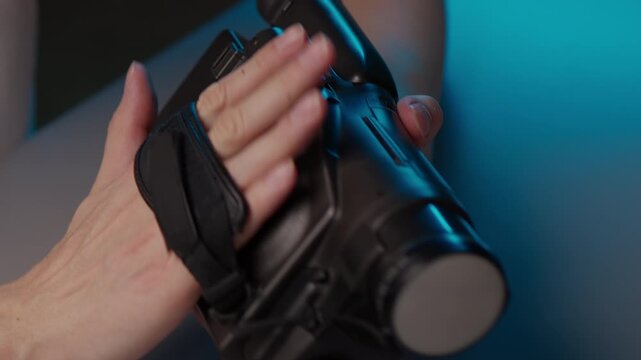 Videographer hands securing classic camcorder by adjusting black strap for firm grip, getting ready to capture memories with old fashioned video equipment in nostalgic setting, close-up, slow motion