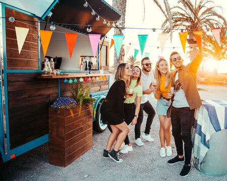 Smiling friends taking selfie on smartphone at sunset