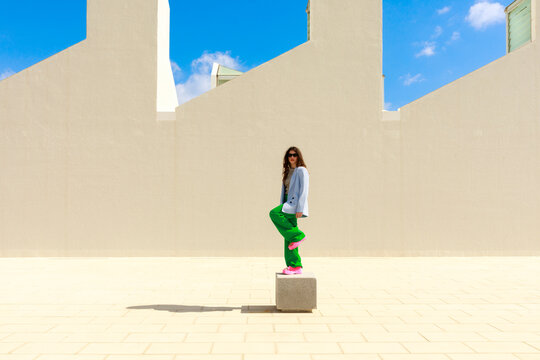 Woman Stands on a Block in front building facade