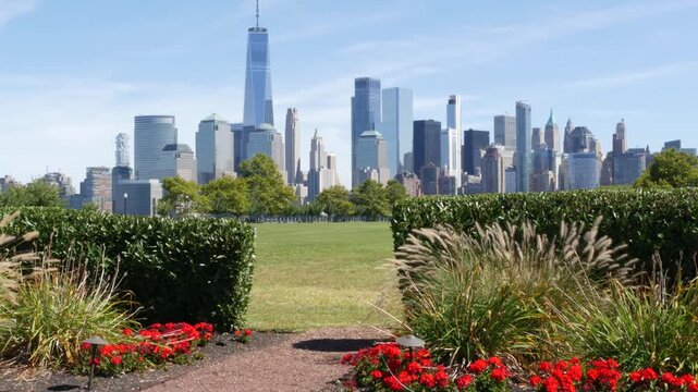 New York City Manhattan Downtown Financial District skyline, World Trade Center tower from New Jersey Liberty state park, United States. Green grass lawn, flowers and skyscraper buildings cityscape.