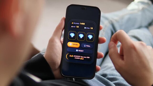 Hit the jackpot. High-quality 4K footage of a user playing a mobile slot game and winning 500 credits. Perfect for gambling apps, online casino promos, and digital entertainment ads. Showcase the