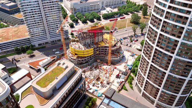 Construction site of a new modern building, Bratislava, Slovakia. Overhead drone shot of cranes and yellow concrete formwork next to high rise towers.