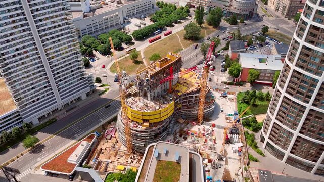 Sunlight over an urban construction site, Bratislava, Slovakia. Elevated view focusing on cranes, yellow formwork structures and building development in the city.