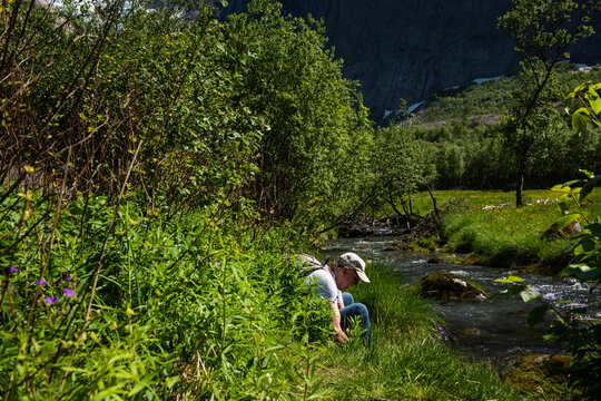 Visitor Enjoying Mountain Stream in Briksdalen Valley, Norway