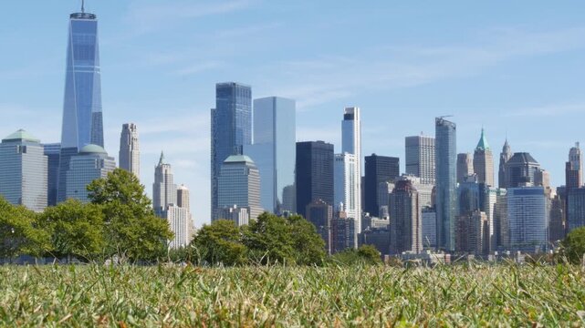New York City Manhattan Downtown Financial District skyline, World Trade Center tower from New Jersey Liberty state park, United States. Green grass lawn and urban cityscape, skyscraper buildings.