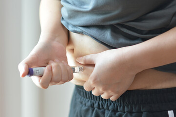Fototapeta na wymiar Hand Holding Weight Loss Injection Pen, Medical Treatment and Healthcare Copcept.