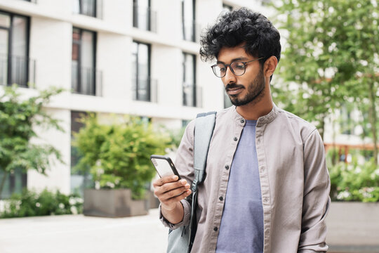 Young handsome man using smartphone in a city. Student man looking at mobile phone. Coffee break, Modern lifestyle, connection, business concept