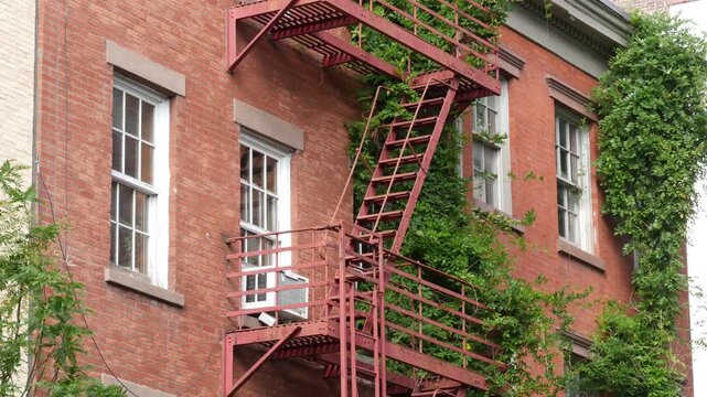 New York City urban residential buildings architecture, Manhattan classic street, United States of America. Typical red brick house in NYC, real estate property in USA. Fire escape metallic ladder.
