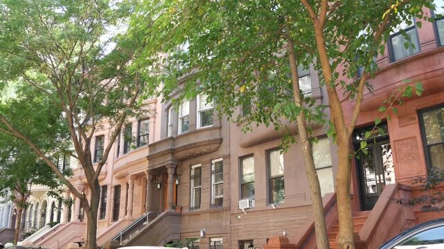 New York City townhouse buildings, brownstone row houses in Manhattan or Brooklyn, United States of America. Classic buildings on residential district street. Real estate property. Rowhouse townhome.