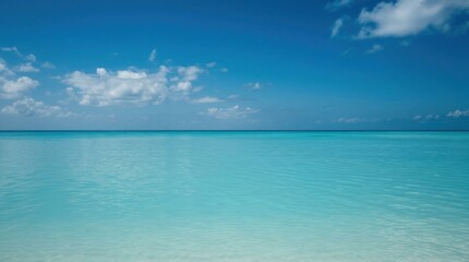 Obraz premium Vast Turquoise Ocean Meets Clear Blue Sky with Wispy Clouds.