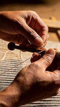 Vertical video: Holding shuttle weaver sleeves rolled wrapping yarn on spool at loom readying weave