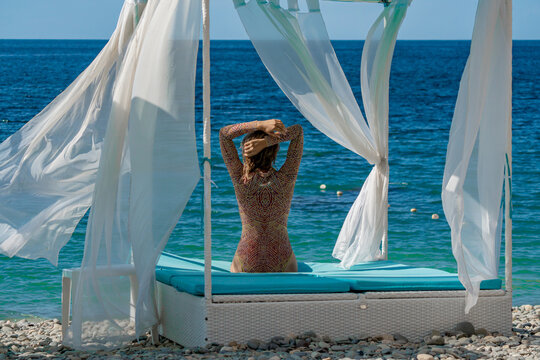 Woman beach ocean relaxing on a daybed by the ocean during a summer vacation