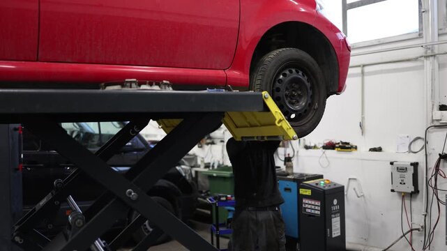 car positioned on a workshop lift with the engine compartment exposed showcasing automotive repair maintenance procedures and technical inspection