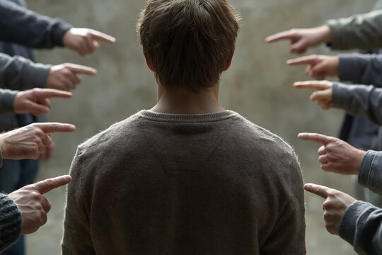 Person facing social pressure surrounded by accusatory pointing hands
