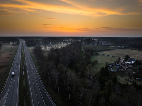 Aerial view of the intersection of A5 and A8 highways surrounded by forests and fields at sunset in Olaine Parish, Olaine Municipality, Latvia.