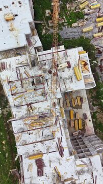 Workers are building a multi-storey structure. The site has various materials like wood and metal scattered across the rooftop. A crane is visible, showing active work on the project.