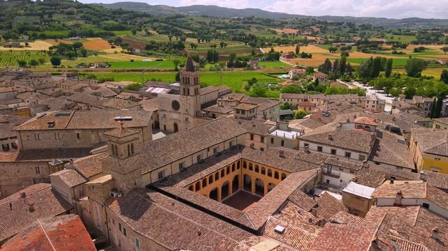 Bevagna Umbria Italy 4k drone dynamic flight over historic town center. Panoramic aerial view of medieval plaza church towers and scenic green fields landscape b-roll most beautiful villages of Italy