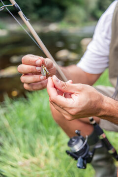 vertical Hispanic fisherman preparing fishing lure by river
