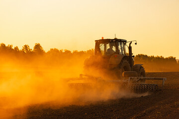 Tractor Working in Field at Sunset with Dust Clouds and Warm Light © NickBalashov