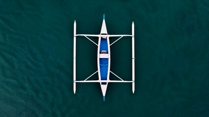 Obraz premium Top-down view of a boat hull with symmetrical outriggers on calm water, minimalist geometric shape.