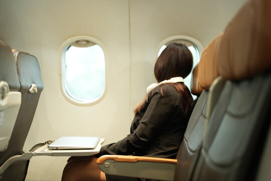Travelers wait in an airport terminal lounge, sitting in chairs and using smartphones before their departing flight.