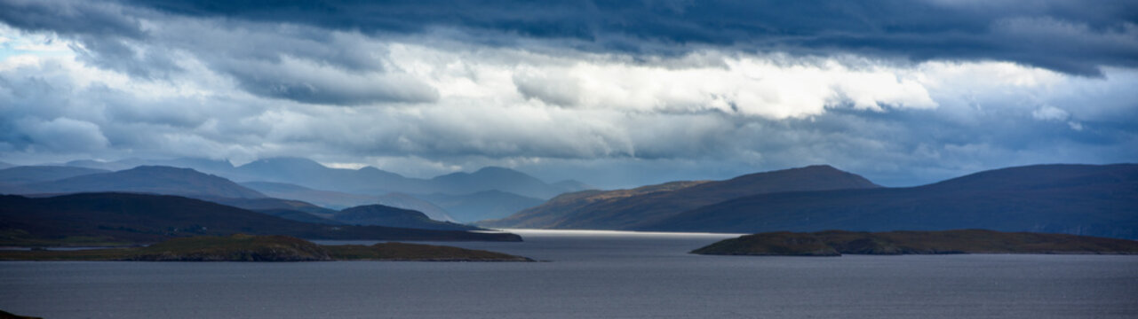 Dramatic clouds gather over a serene sea loch surrounded by rolling hills capturing the tranquility of the Scottish Highlands at dusk