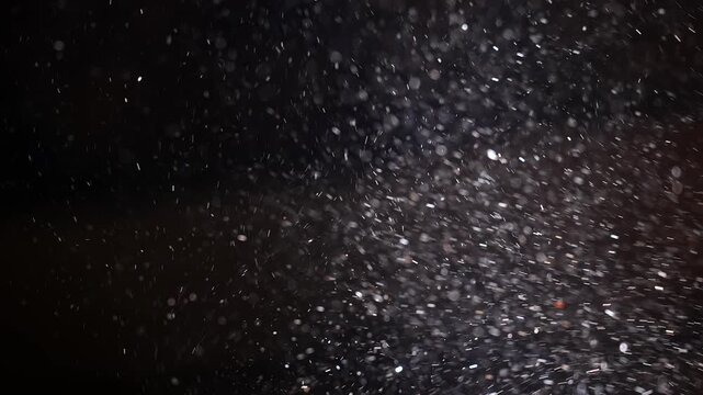 Fine dust particles suspended in air and illuminated by a strong spotlight against a dark background. Concept atmosphere, texture, lighting, theater, cinema, air quality, environment and abstract