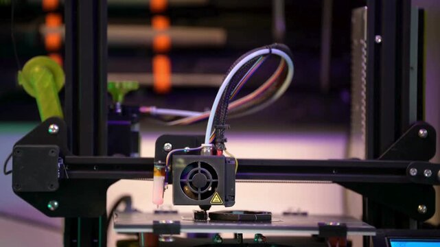 Closeup of a 3d printer nozzle extruding filament onto a print bed