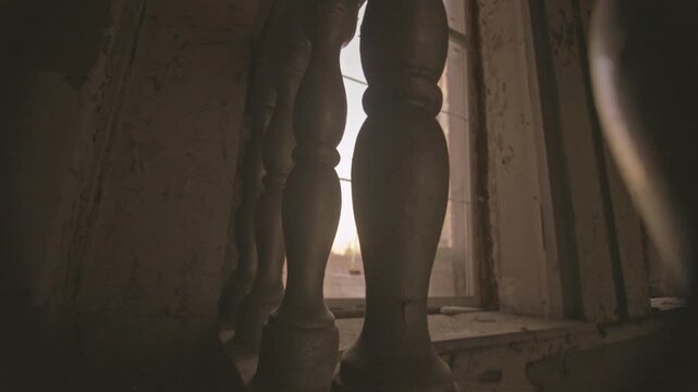 An old wooden banister with a textured surface is illuminated by soft light from a nearby window. Concept of vintage architecture, interior design inspiration, and historical elegance.