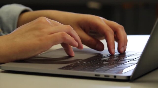 Close-up of hands typing on a modern laptop keyboard, Professional working on a laptop computer in the office, Detail of fingers typing text on a laptop at a desk, Person working remotely 