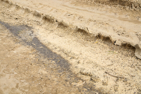 Deep tire tracks imprinted on dry mud road surface, textured car wheel tread marks on country ground path close up
