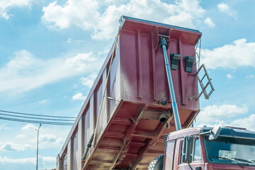 Heavy duty dumper truck with raised red tipper body unloading ca © kalyanby