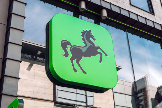 Green signage featuring the black horse 'Cancara' Lloyds logo, on the glass frontage of Lloyds Bank, Manchester.
