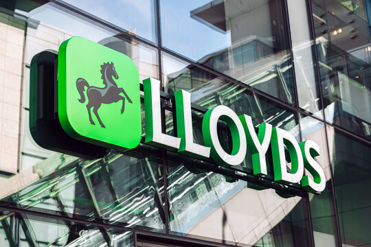 Green signage featuring the black horse 'Cancara' Lloyds logo, on the glass frontage of Lloyds Bank, Manchester.