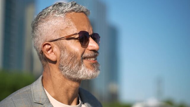 Close up portrait of confident mature Brazilian businessman with sunglasses looking forward empowered in modern urban city