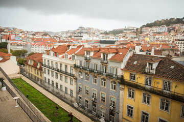 Obraz premium Panoramic view of Lisbon rooftops and steep streets in Portugal. Scenic urban landscape featuring historic architecture and dense city layout under cloudy skies.