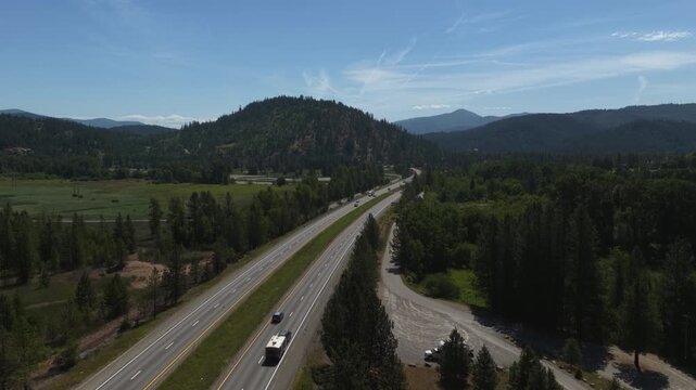 Aerial of Interstate 90 through forested valley near Cataldo Idaho on sunny summer day