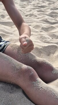 Child playing with fine sand, letting it slip through both hands in a time concept video about experience and passing time. Close up