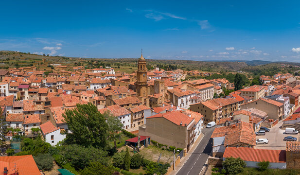 Panoramic elevated view of La Iglesuela del Cid, medieval village with baroque church tower above terracotta rooftops, arid Maestrazgo plateau landscape, Teruel, Aragon, Spain