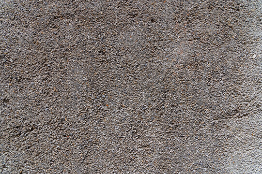 Exposed aggregate concrete texture background. Close-up view of a rough wall surface made of small pebbles, gravel, and cement