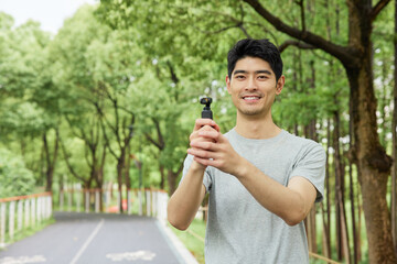 Smiling young man holding a handheld device on a park path © HaXuanDieu